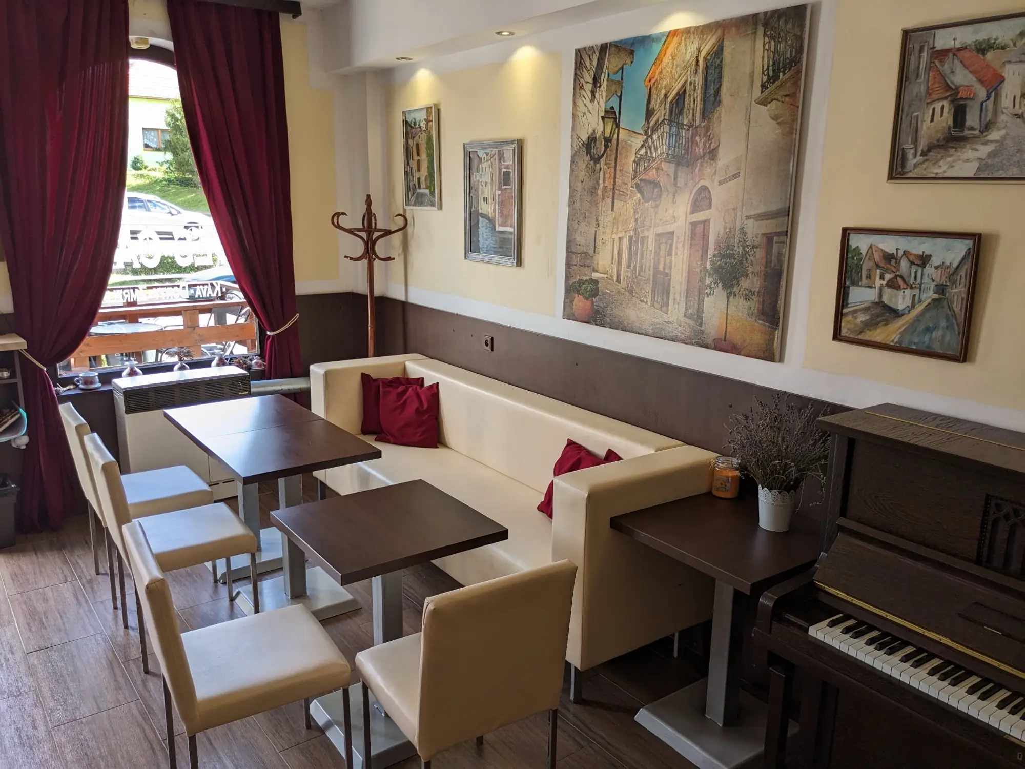 Interiér kavárny Ves-Cafe s posezením, obrazy a pianem